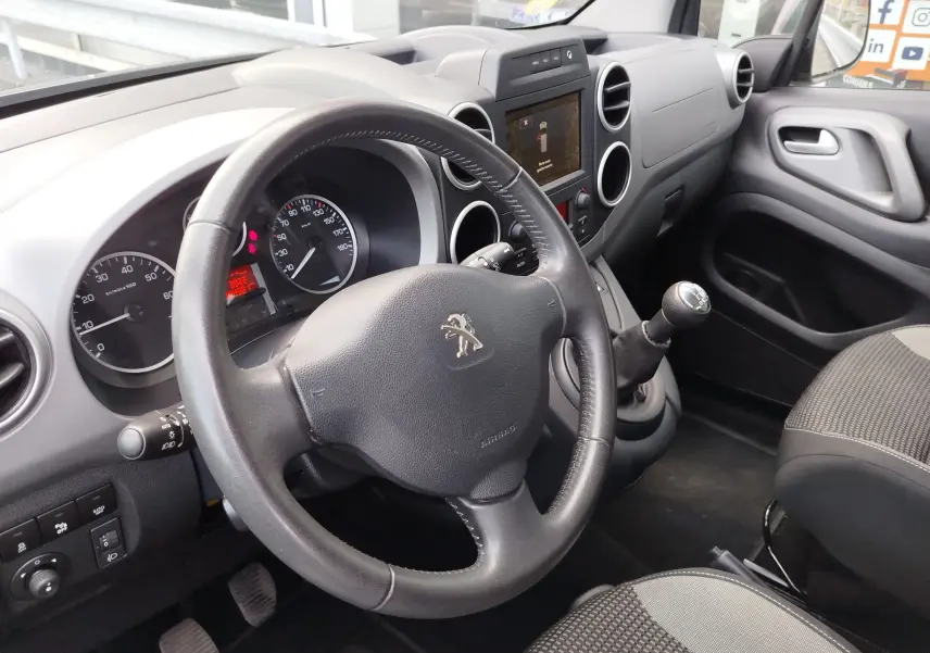 Vue intérieure côté conducteur du Peugeot Partner Tepee 2017, volant cuir, levier de vitesse manuel et tableau de bord gris.