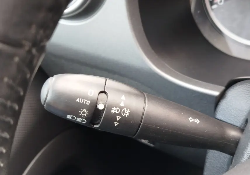 Gros plan sur la manette de commandes des phares et clignotants à gauche du volant dans un Peugeot Partner Tepee gris foncé 2017.