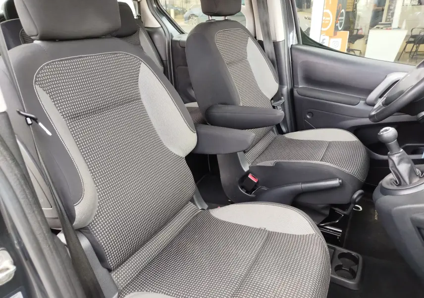 Vue intérieure côté conducteur du Peugeot Partner Tepee 2017, sièges tissu gris foncé avec accoudoirs et levier de vitesse manuel.