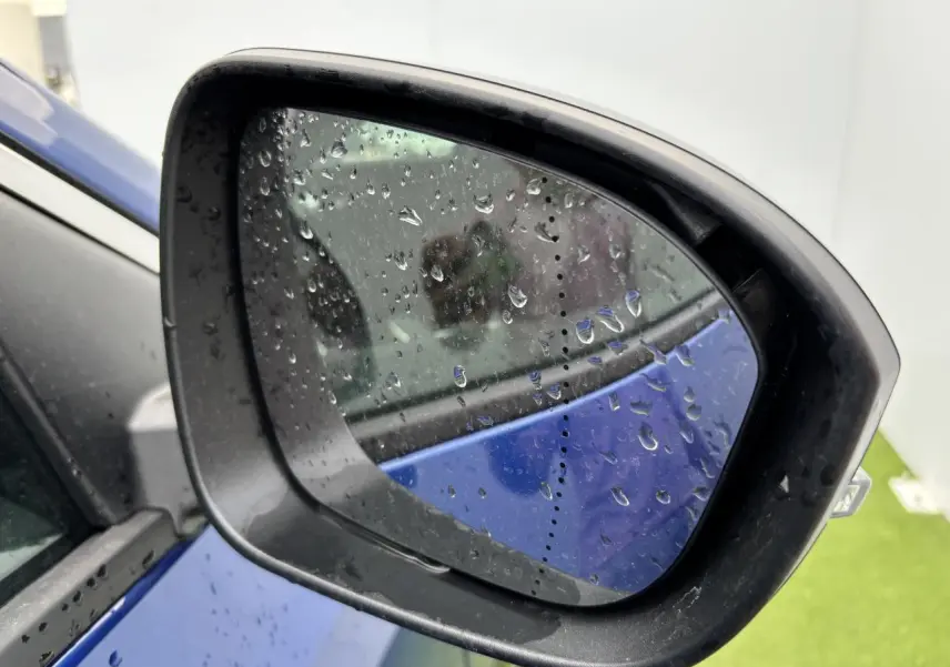 Rétroviseur côté gauche d'un Renault Austral bleu Iron Metal avec gouttes de pluie sur le miroir.