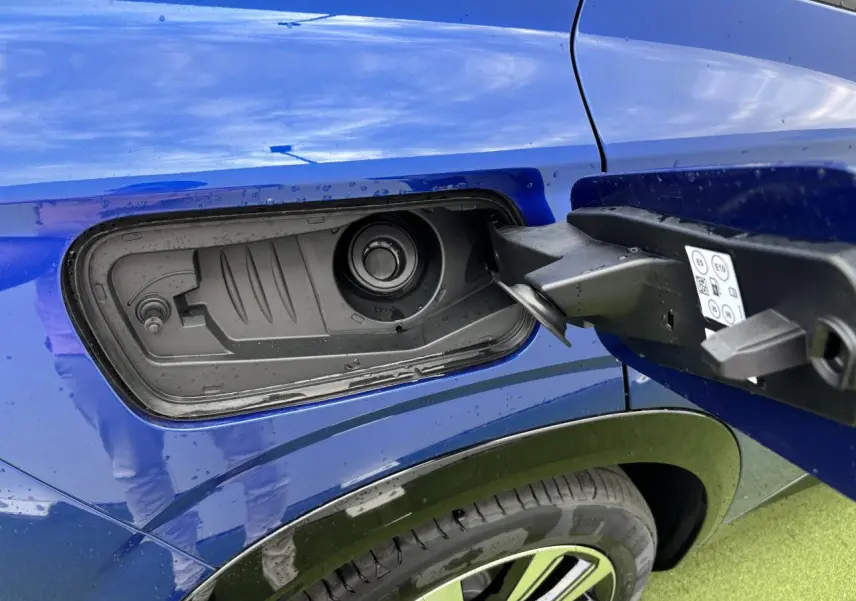 Gros plan sur la trappe de carburant côté gauche du Renault Austral bleu Iron Metal avec jante alliage 19 pouces visible.