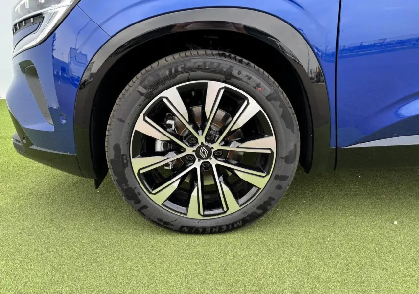 Gros plan sur la jante alliage noire et diamantée 19 pouces du côté avant gauche du Renault Austral bleu Iron Metal.