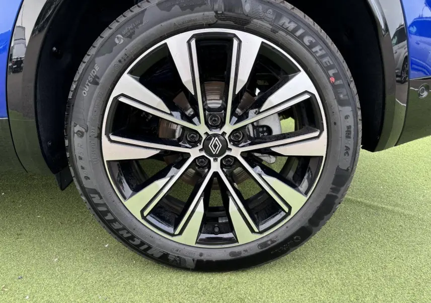 Gros plan sur la jante alliage noire et argentée du Renault Austral bleu Iron Metal, avec logo Renault au centre.