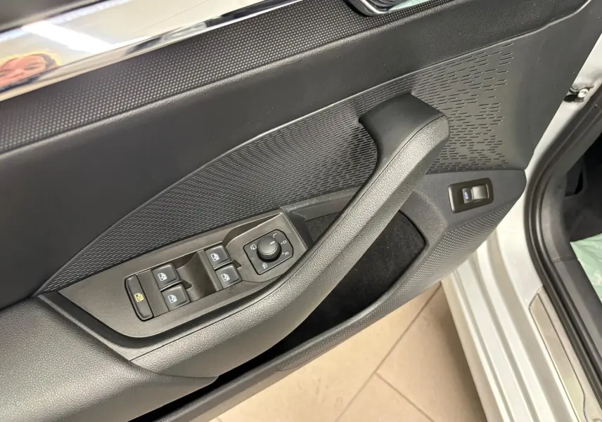 Gros plan sur la porte côté conducteur de la Skoda Octavia Combi gris argent 2023, avec commandes des vitres et rétroviseurs.