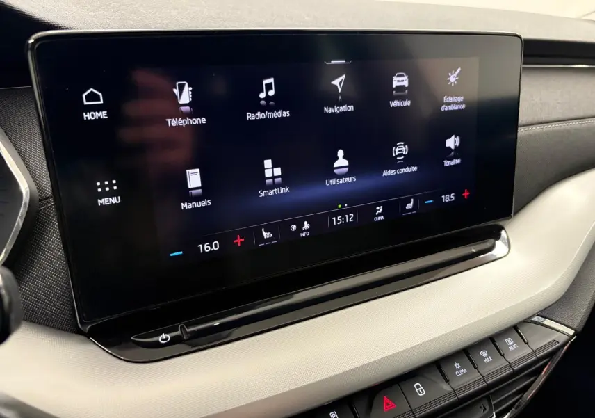 Écran tactile central du tableau de bord de la Skoda Octavia Combi gris argent 2023, affichant menu multimédia et climatisation.
