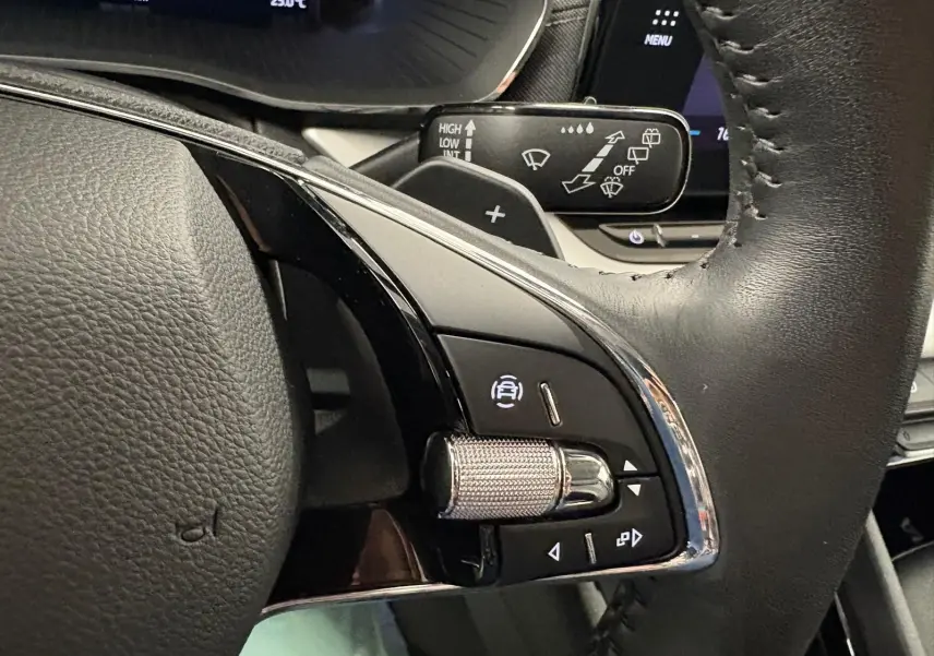 Gros plan sur la commande de régulateur de vitesse au volant cuir noir d'une Skoda Octavia Combi gris argent 2023.