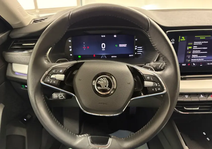 Vue intérieure centrée sur le volant cuir noir d'une Skoda Octavia Combi 2023, avec tableau de bord numérique et écran tactile.