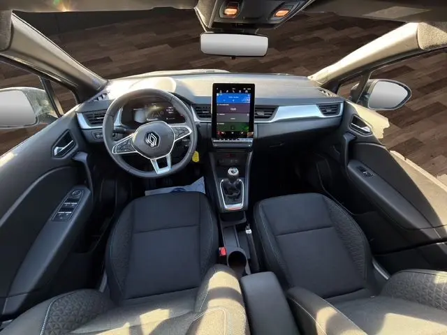 Vue intérieure avant du Renault Captur 2024 avec tableau de bord numérique, écran tactile vertical et sellerie tissu noire.