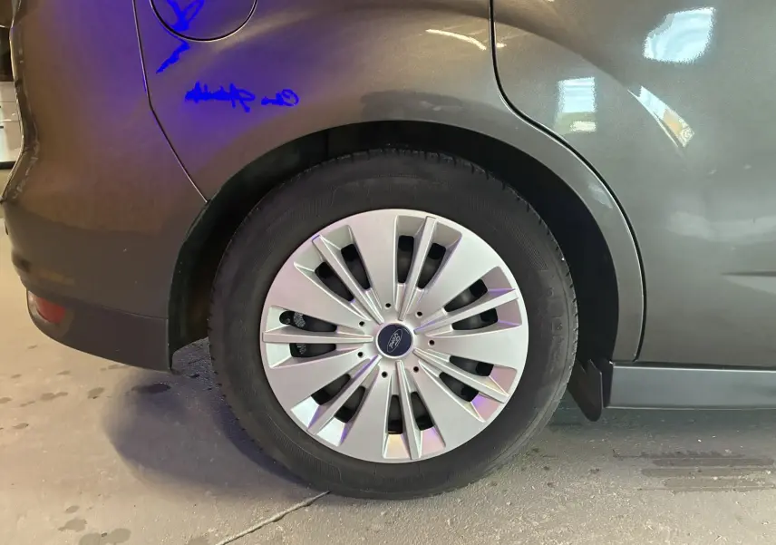 Gros plan sur la roue arrière gauche d'une Ford C-MAX gris métallisé avec enjoliveur à rayons fins.