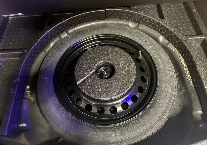 Gros plan sur la roue de secours noire logée dans le coffre d'une Ford C-MAX gris 2015.