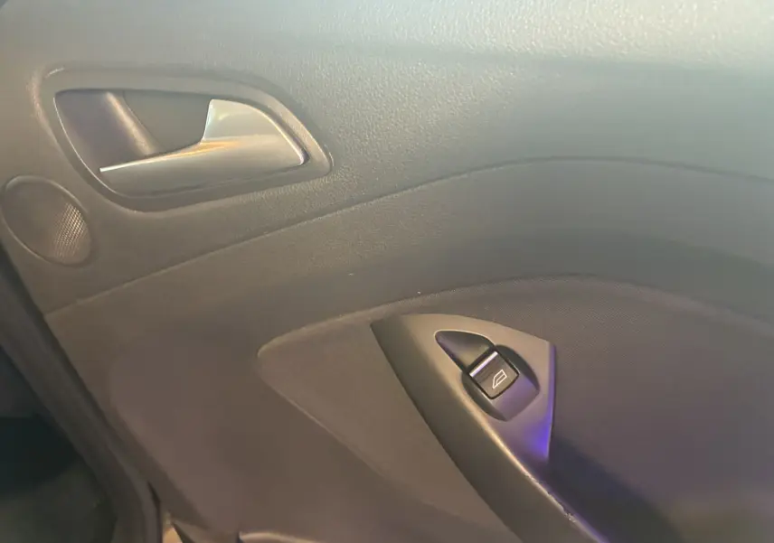 Gros plan sur la poignée intérieure et le bouton de lève-vitre côté gauche d'une Ford C-MAX gris 2015.