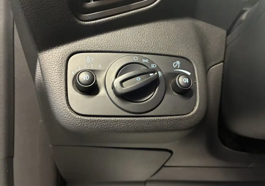 Gros plan sur le panneau de commande des phares d’un Ford C-MAX gris de 2015, avec boutons de réglage et interrupteur rotatif.