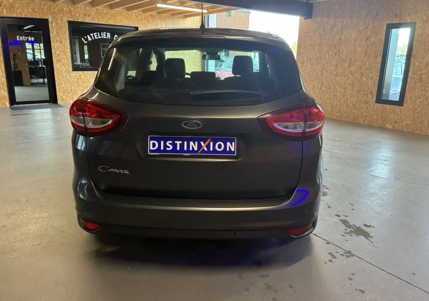 Vue arrière d'une Ford C-MAX gris foncé 2015 garée en intérieur avec plaque d'immatriculation Distinxion visible.
