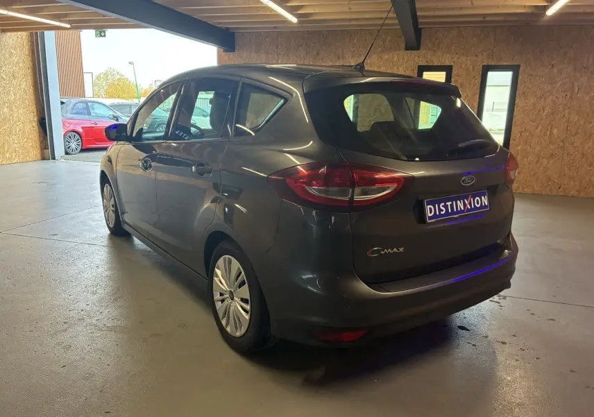 Vue 3/4 arrière droite d'une Ford C-MAX gris foncé garée en intérieur, avec feux arrière et logo visibles.