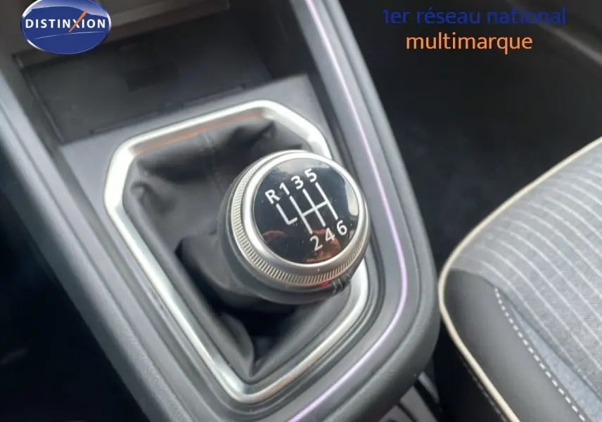 Gros plan sur le levier de vitesses manuel de la Renault Clio 2025, avec coutures grises et tissu rayé du siège visible.