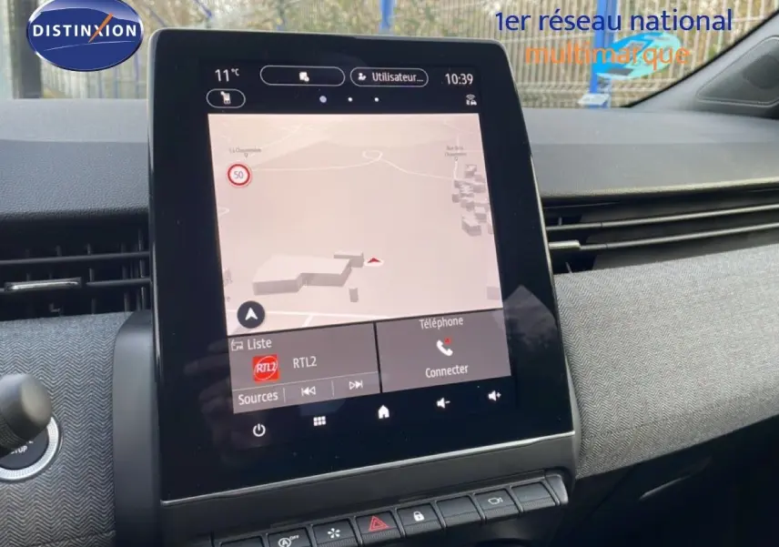 Vue rapprochée de l’écran tactile central de la Renault Clio rouge Désir Métal 2025, affichant la navigation et les commandes multimédia.
