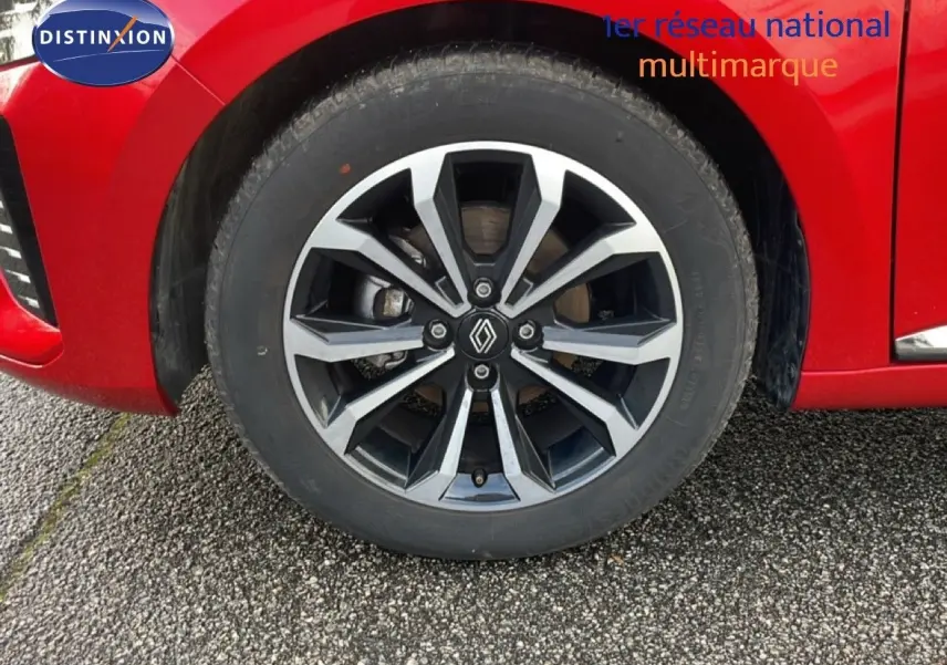 Gros plan sur la roue avant gauche d'une Renault Clio rouge Désir Métal avec jante alliage noire et argent.