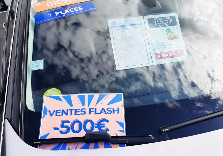 Vue avant rapprochée du pare-brise d’un Peugeot 5008 gris 2019 avec étiquettes diesel, 7 places et promotion -500€.