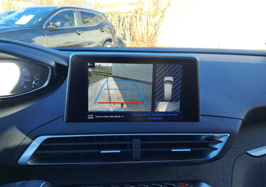 Vue intérieure du tableau de bord du Peugeot 5008 gris de 2019, avec écran affichant la caméra de recul et les capteurs de stationnement.