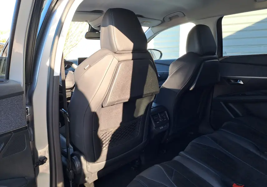 Vue intérieure arrière du Peugeot 5008 gris 2019, montrant les sièges avant en cuir noir et la banquette arrière.