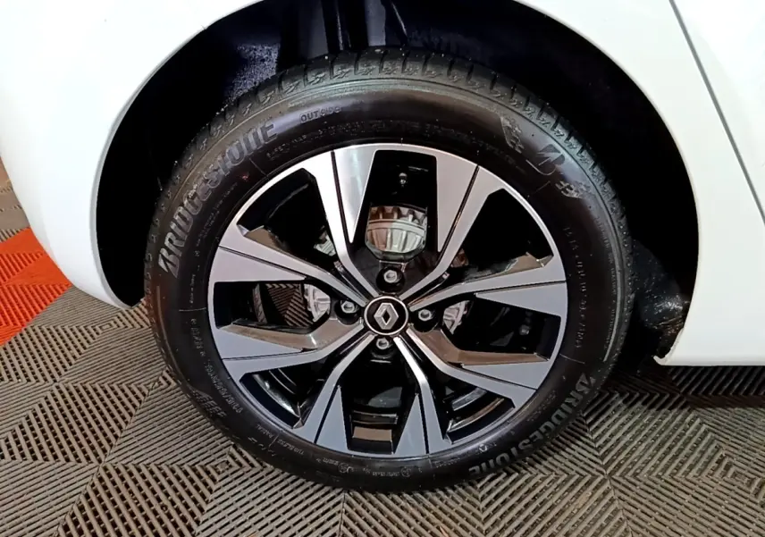 Gros plan sur la roue avant droite blanche d'une Renault Clio 2023 avec jante alliage noire et argentée.