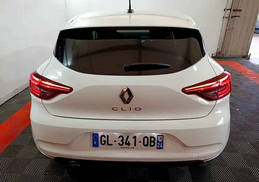 Vue arrière d'une Renault Clio blanche 2023 avec feux LED allumés dans un garage fermé.