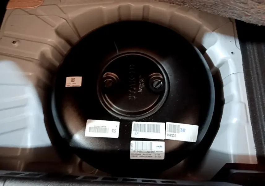 Vue rapprochée du réservoir GPL noir dans le coffre blanc d’une Renault Clio Business TCe 100 GPL 2023.