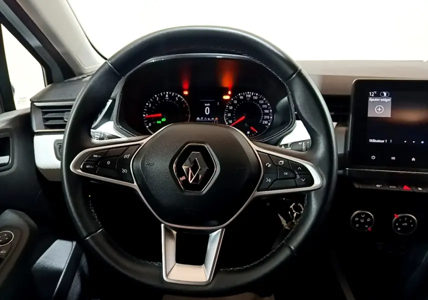 Vue intérieure centrée sur le volant noir de la Renault Clio 2023 avec tableau de bord et écran tactile visible à droite.