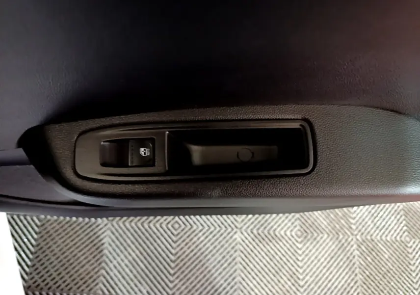 Gros plan sur la commande de lève-vitre côté intérieur d'une porte de Renault Clio Business blanc, 2023.