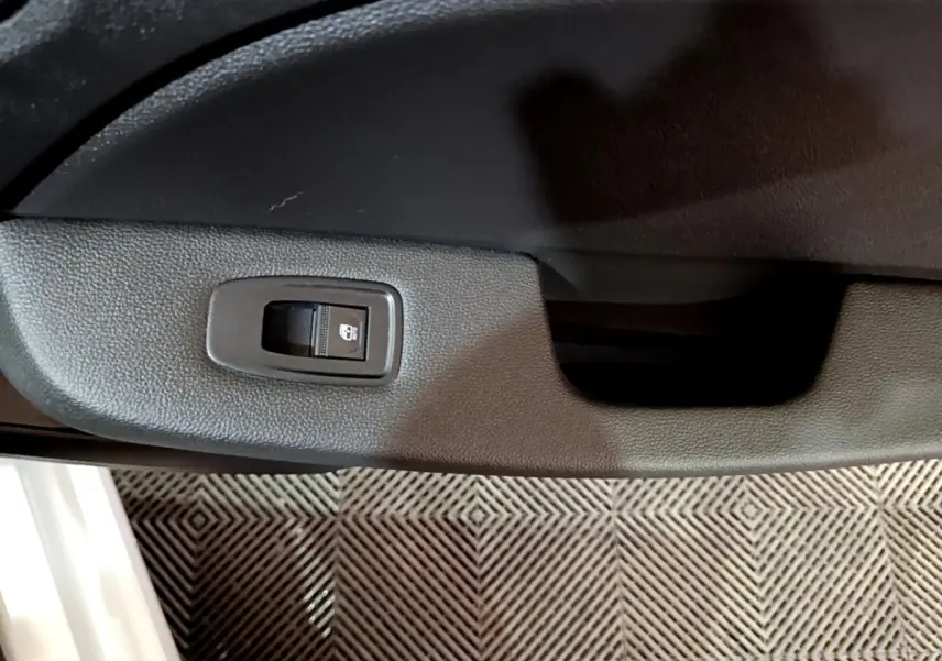 Détail de la commande de verrouillage des portes sur la portière intérieure côté conducteur d’une Renault Clio blanche.