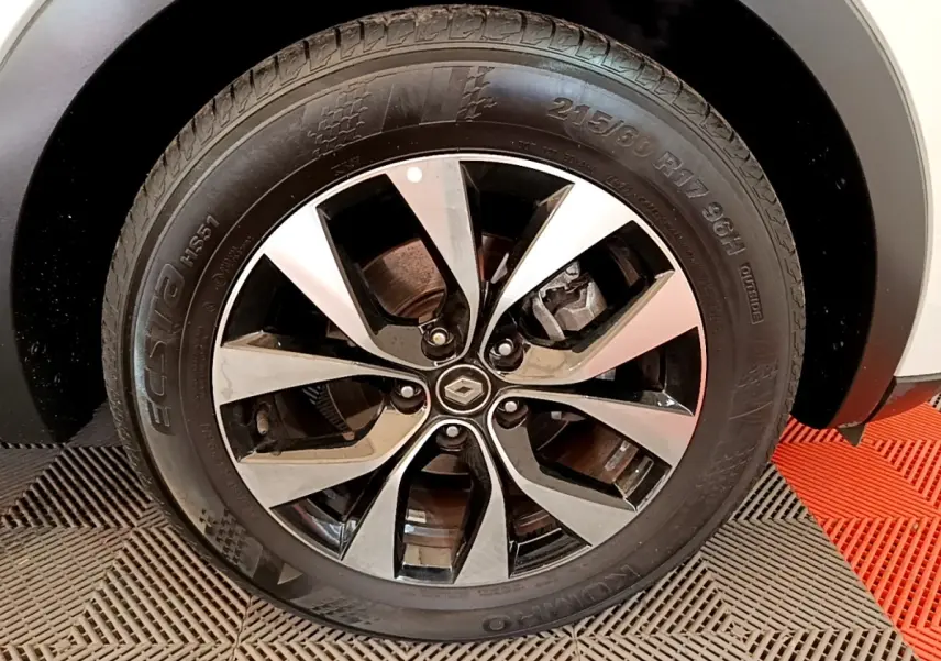 Gros plan sur la roue avant droite du Renault Arkana blanc, mettant en valeur la jante alliage bicolore et le logo central.