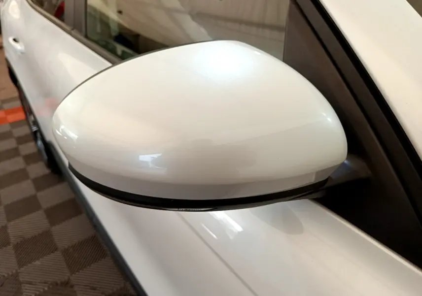 Rétroviseur côté gauche blanc du Renault Arkana Evolution E-Tech 145, vue rapprochée en intérieur.