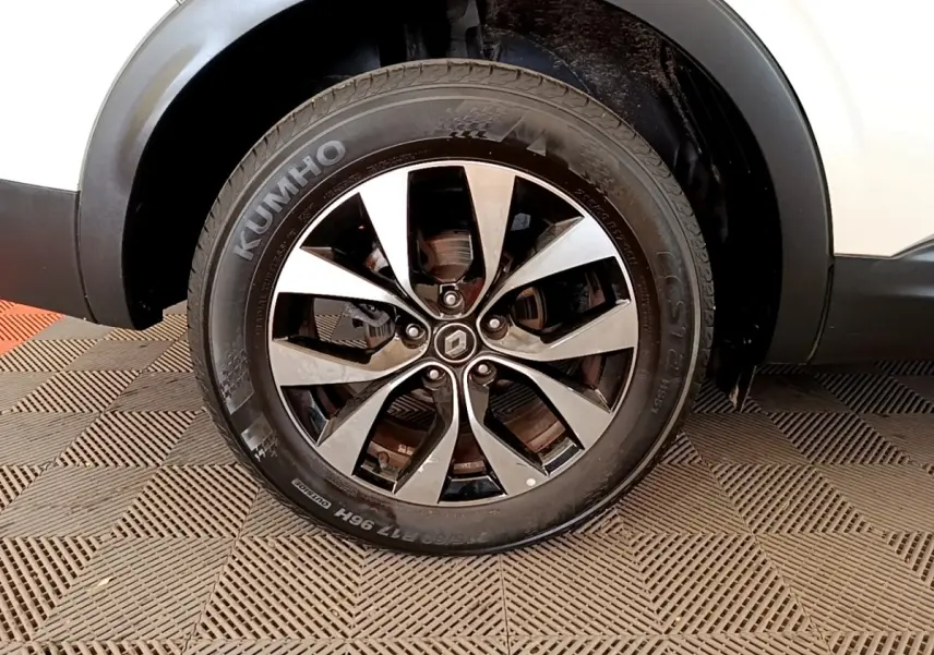 Gros plan sur la roue avant droite d’un Renault Arkana blanc, avec jante alliage bicolore et pneu Kumho.