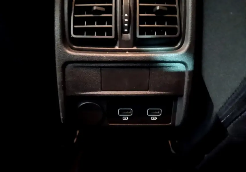 Gros plan sur la console arrière noire du Renault Arkana Evolution E-Tech avec prises USB et aérateurs visibles.