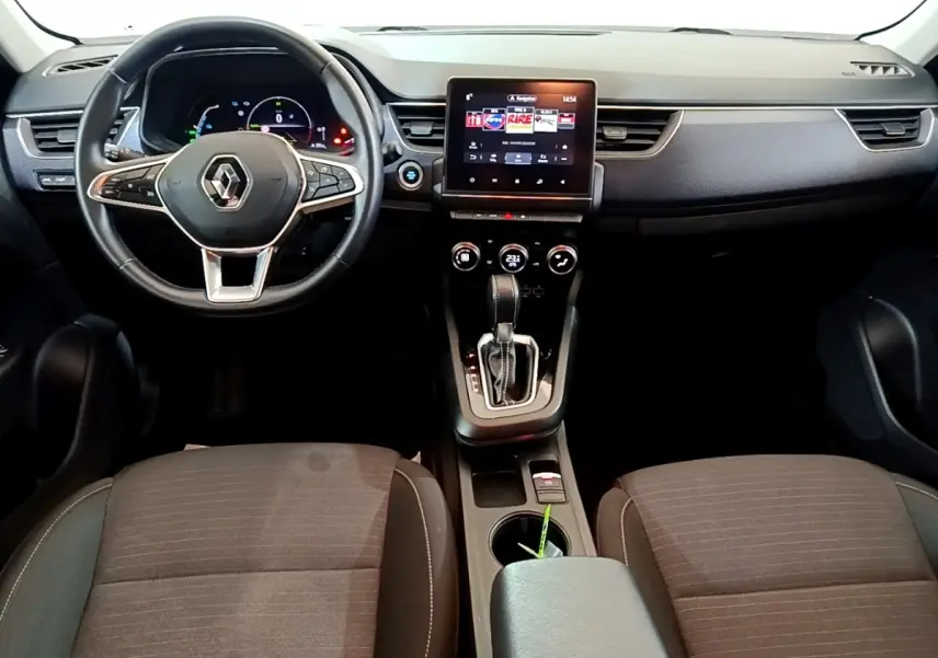 Vue intérieure avant du tableau de bord et console centrale du Renault Arkana blanc avec écran tactile vertical et volant multifonctions.