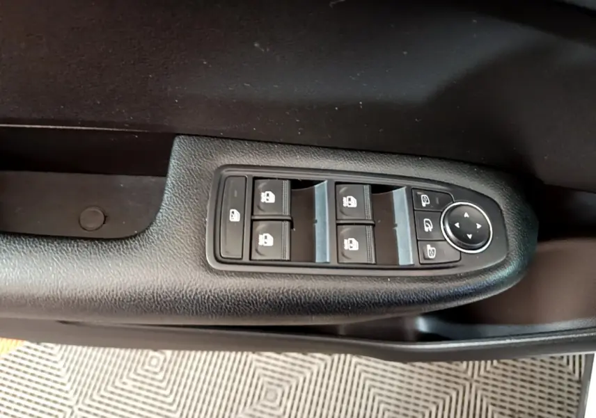 Vue rapprochée des commandes de lève-vitres et rétroviseurs sur la porte côté conducteur d’une Renault Arkana blanc.