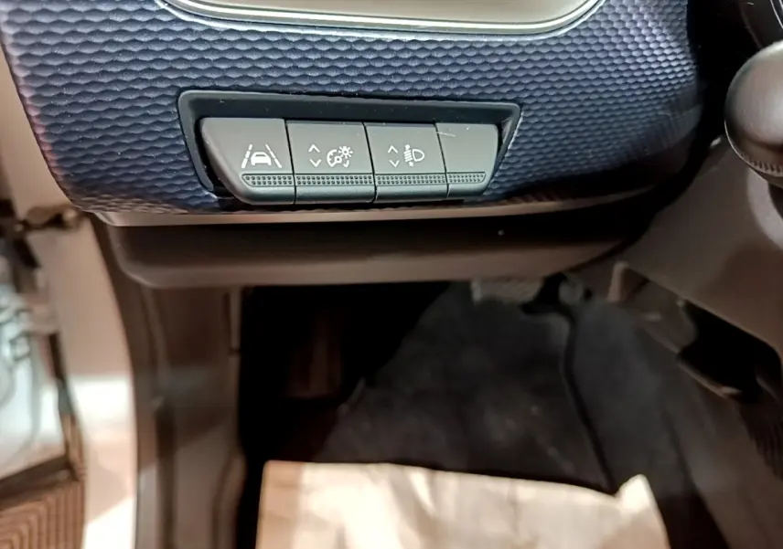 Détail des commandes d'assistance à la conduite sur tableau de bord bleu foncé intérieur Renault Arkana blanc.