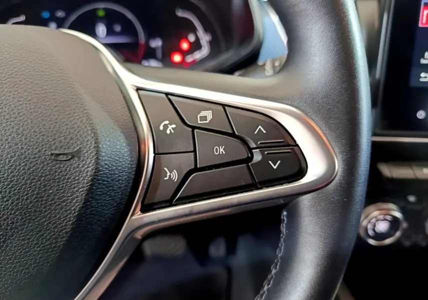 Gros plan sur les commandes multifonctions à droite du volant cuir du Renault Arkana blanc, tableau de bord en arrière-plan.