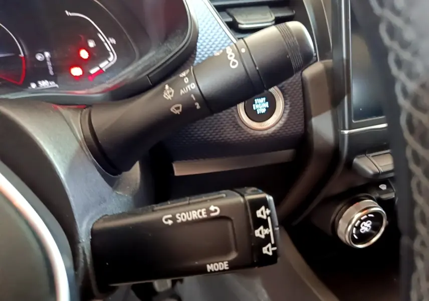 Gros plan sur la commande multifonction noire et le bouton start/stop éclairé du tableau de bord du Renault Arkana blanc.