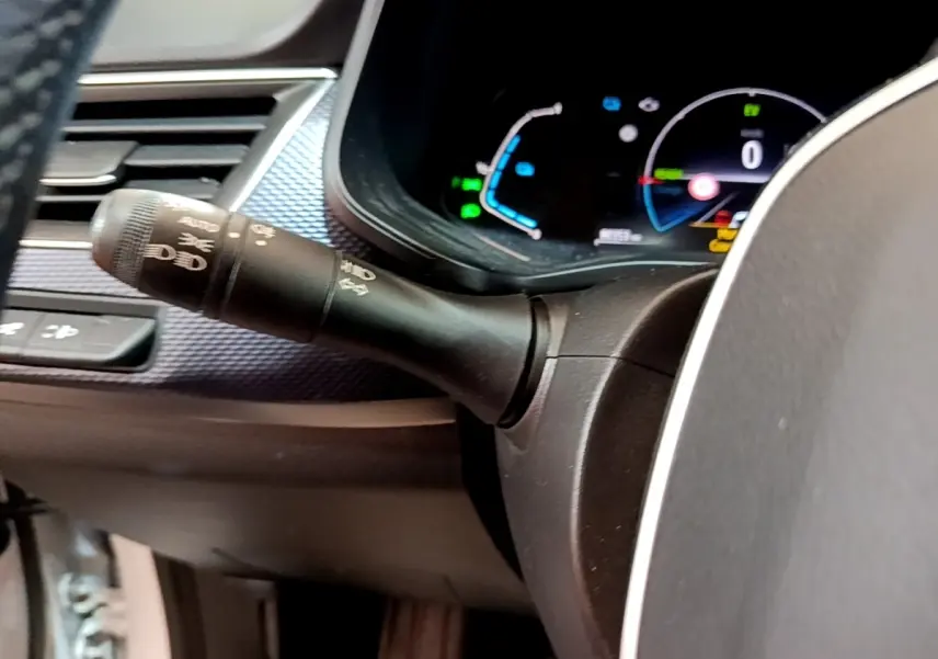 Gros plan sur la manette des phares et le combiné d'instruments numérique du tableau de bord du Renault Arkana blanc.