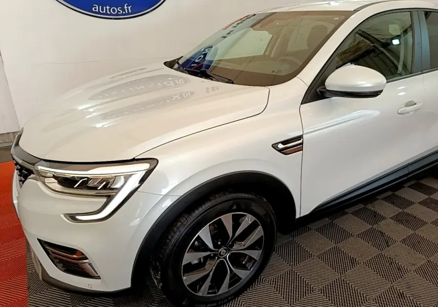 Renault Arkana blanc en vue 3/4 avant droit, avec phares LED et jantes alliage distinctives.