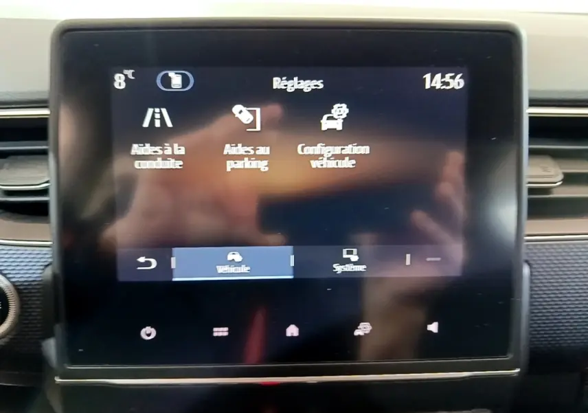 Écran tactile central du tableau de bord du Renault Arkana blanc, affichant les réglages d’aides à la conduite et au parking.