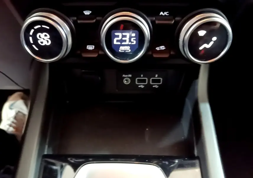 Gros plan sur la console centrale du Renault Arkana Evolution E-Tech 2023, montrant les commandes de climatisation et ports USB.