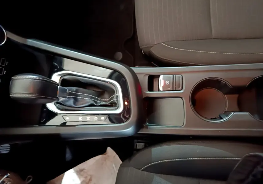 Vue plongeante sur la console centrale noire avec levier de vitesse automatique et frein à main électrique du Renault Arkana blanc.