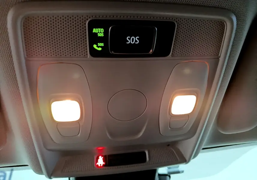 Vue intérieure en gros plan du plafonnier avec boutons d’éclairage et alerte SOS allumée dans une Renault Arkana blanche.