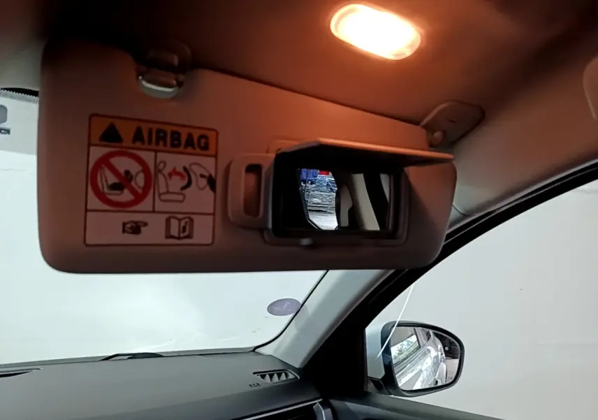 Intérieur du Renault Arkana blanc, vue côté passager avec pare-soleil et miroir éclairé ouvert.