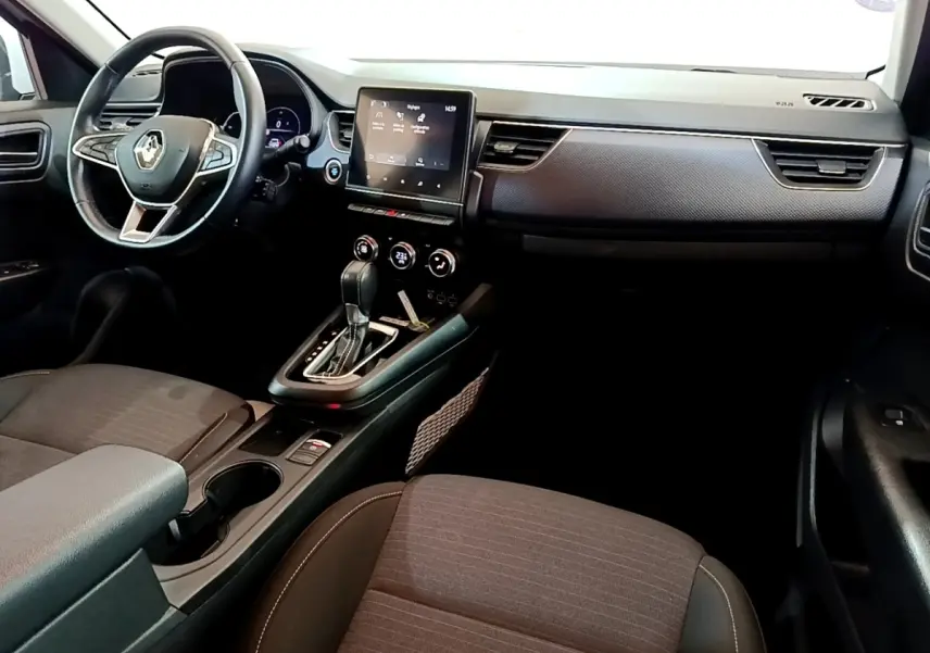 Intérieur de la Renault Arkana Evolution E-Tech 2023 vu côté passager, tableau de bord noir avec écran tactile central.