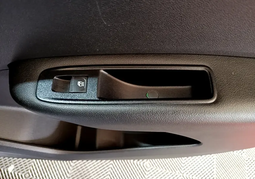 Gros plan sur la poignée intérieure noire et le bouton de verrouillage de porte côté conducteur du Renault Arkana blanc 2023.