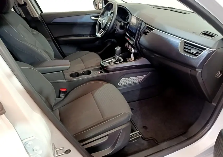 Vue intérieure côté conducteur du Renault Arkana blanc, mettant en valeur le tableau de bord et la console centrale moderne.