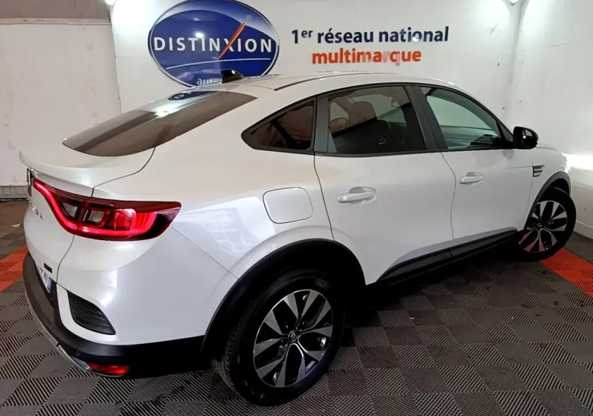 Renault Arkana blanc en 3/4 arrière droit, feux LED allumés et jantes alliage distinctives visibles.